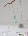 Side angle of minimalist aquamarine necklace, showing polished gemstone in claw setting, 925 sterling silver