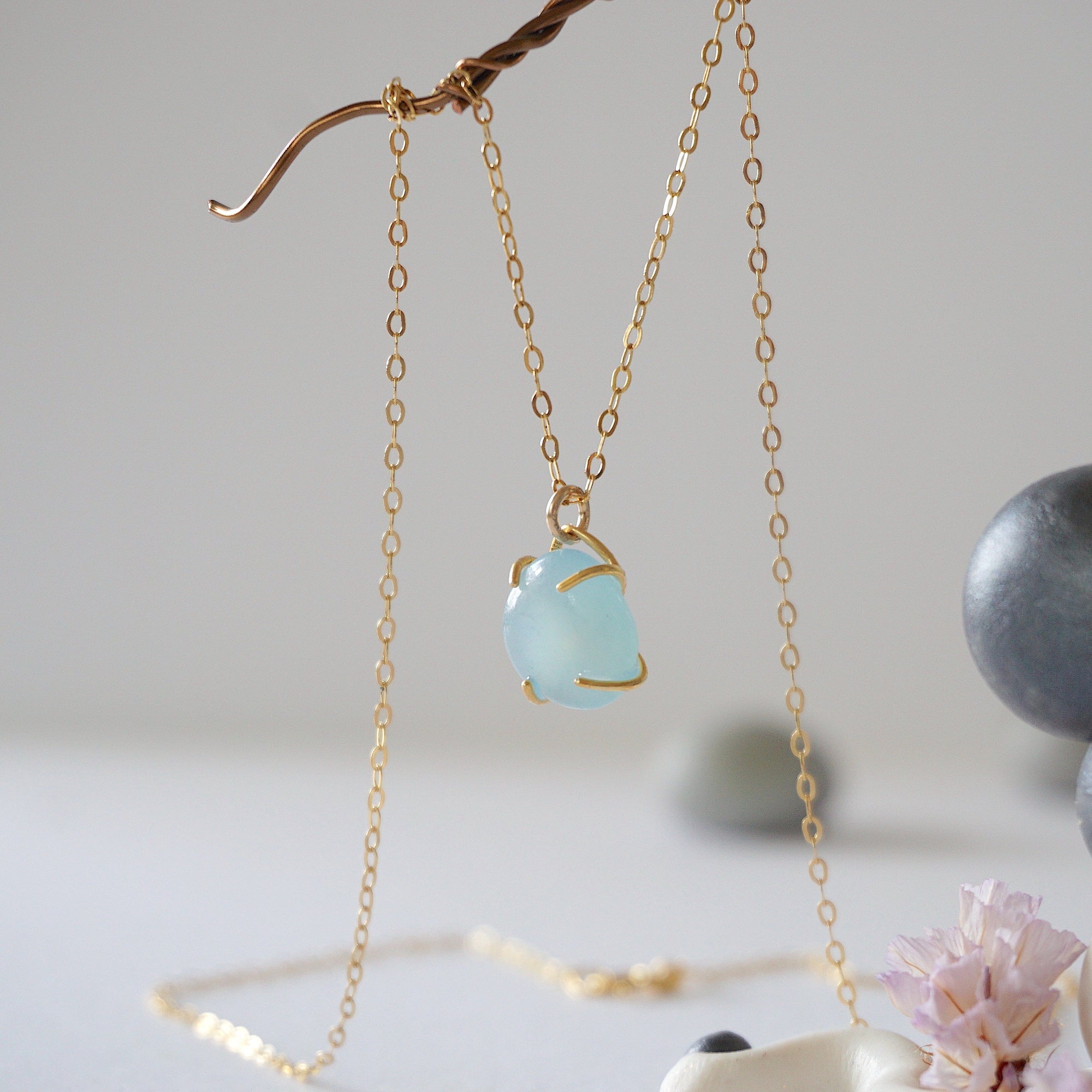 Side angle of minimalist aquamarine necklace in gold, showing polished gemstone in claw setting, 14k gold vermeil