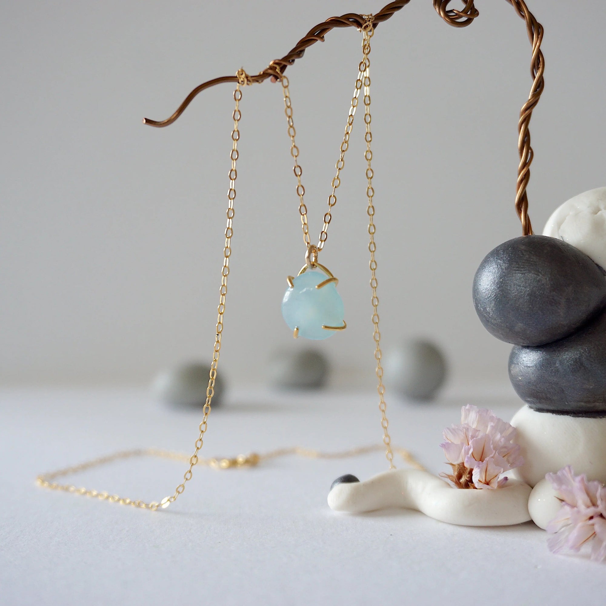Zoomed out view of minimalist aquamarine necklace in gold, hanging on display, artisan claw setting, gold filled chain