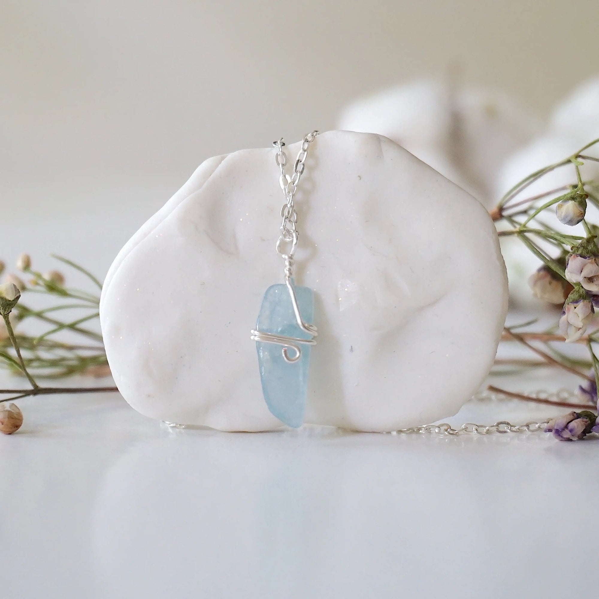 Back side angle of minimalist aquamarine necklace, showing simple wire wrapping and silver plated chain
