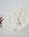 Minimalist aquamarine necklace hanging on display, detailed front view, genuine 8mm aquamarine bead, soft silver finish wire, Designs by Nature Gems