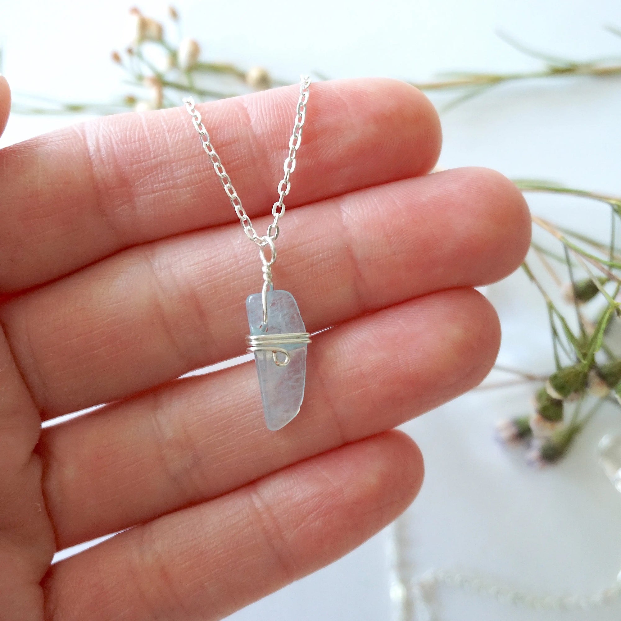 Minimalist aquamarine necklace in a hand for size reference, genuine aquamarine, soft silver artisan wire wrapping, Designs by Nature Gems