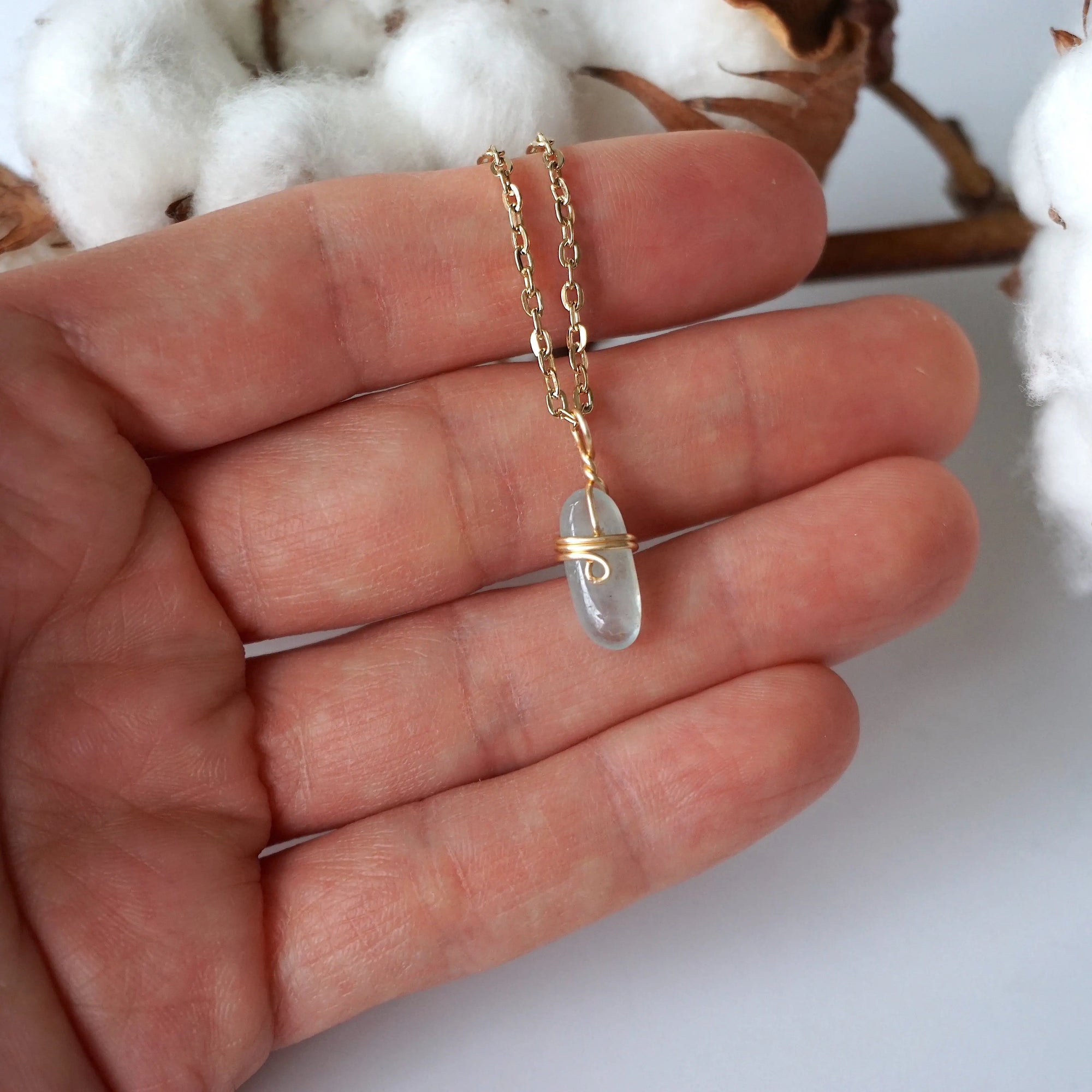 Minimalist aquamarine necklace in a hand for size reference, genuine aquamarine, warm gold artisan wire wrapping, Designs by Nature Gems
