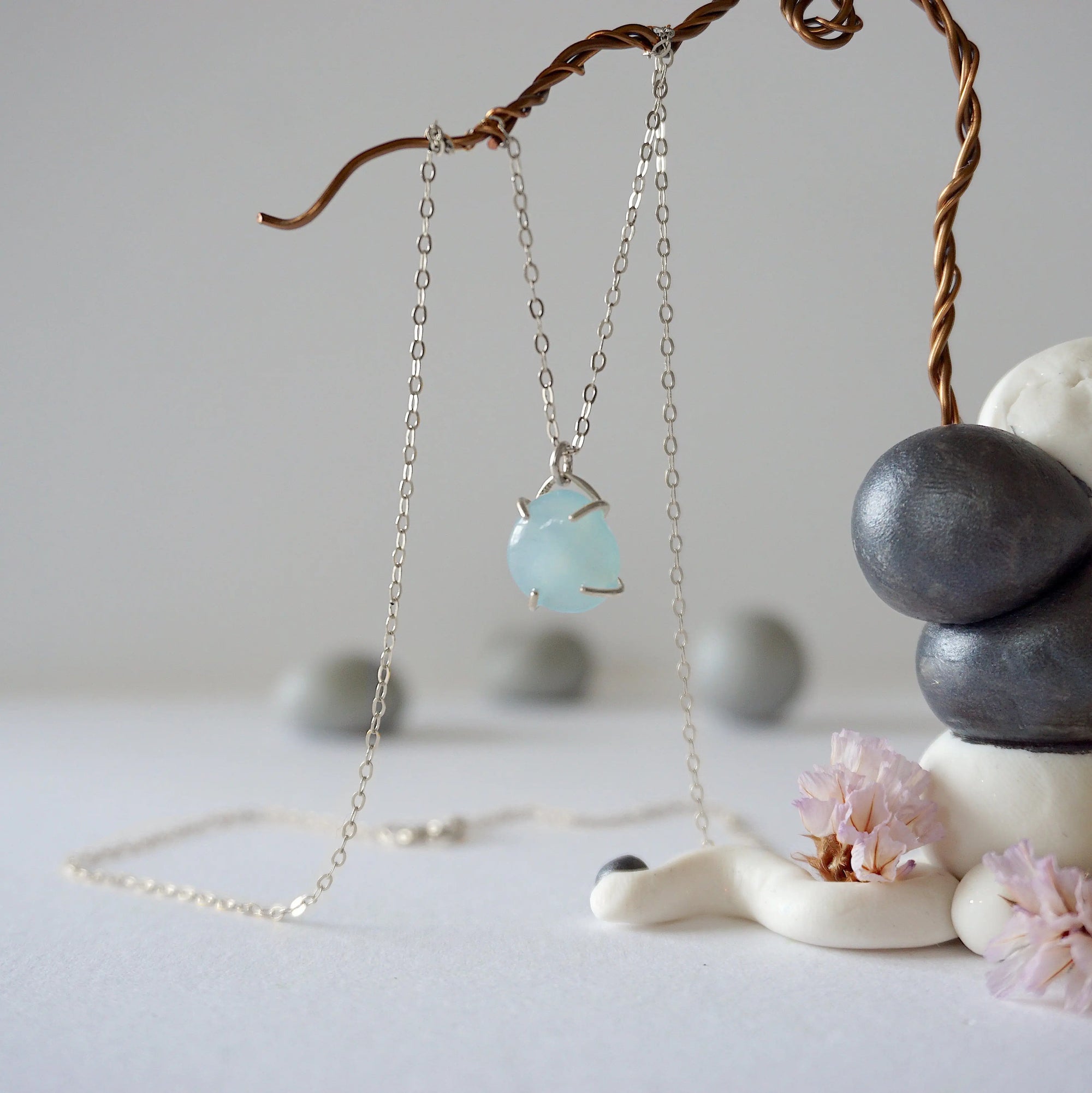 Zoomed out view of minimalist aquamarine necklace hanging on display, artisan claw setting, sterling silver chain