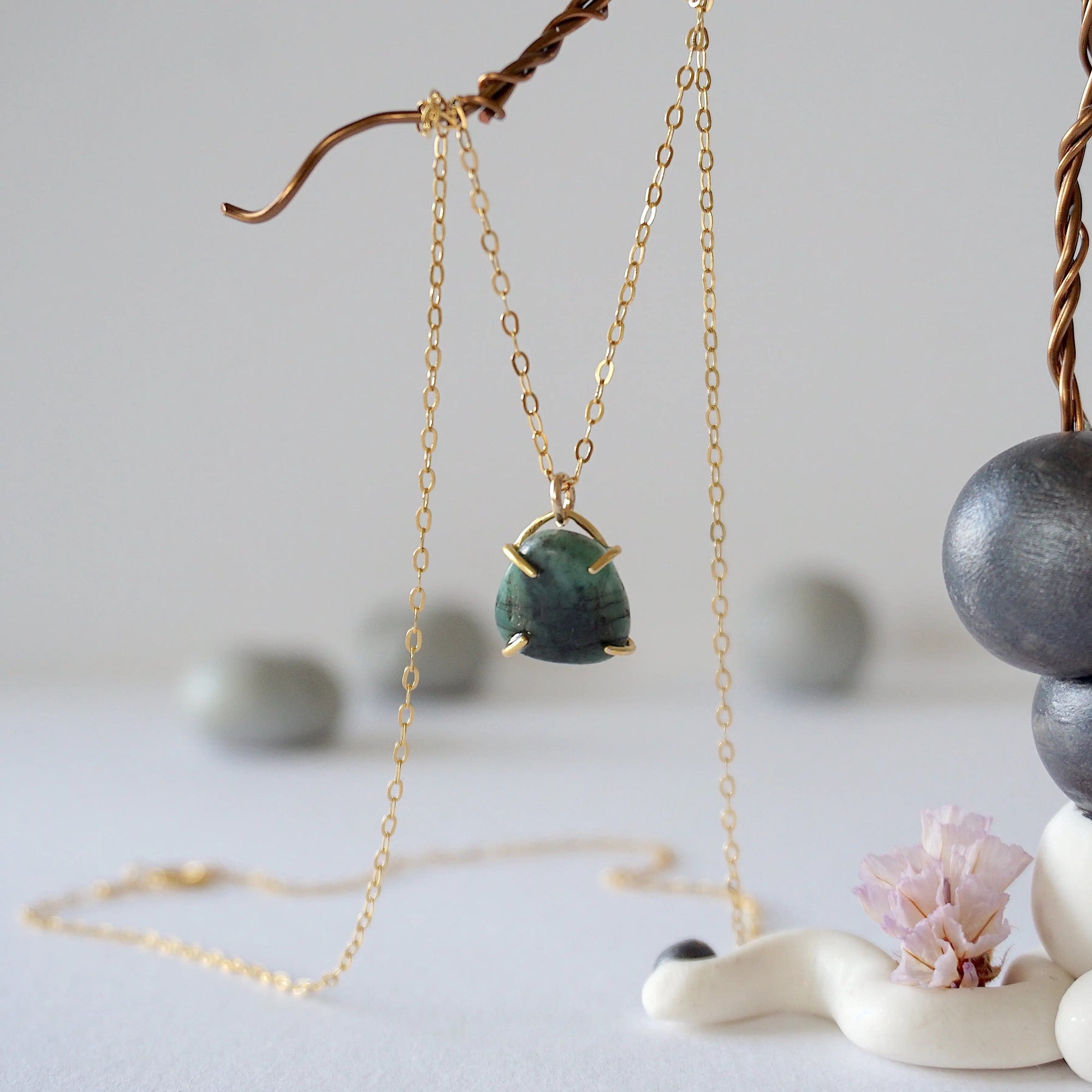 Front view of minimalist emerald necklace in gold vermeil with natural polished-raw emerald pendant for women.