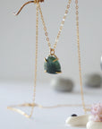 Side angle view of minimalist emerald necklace showing gold vermeil prong setting and natural raw emerald.