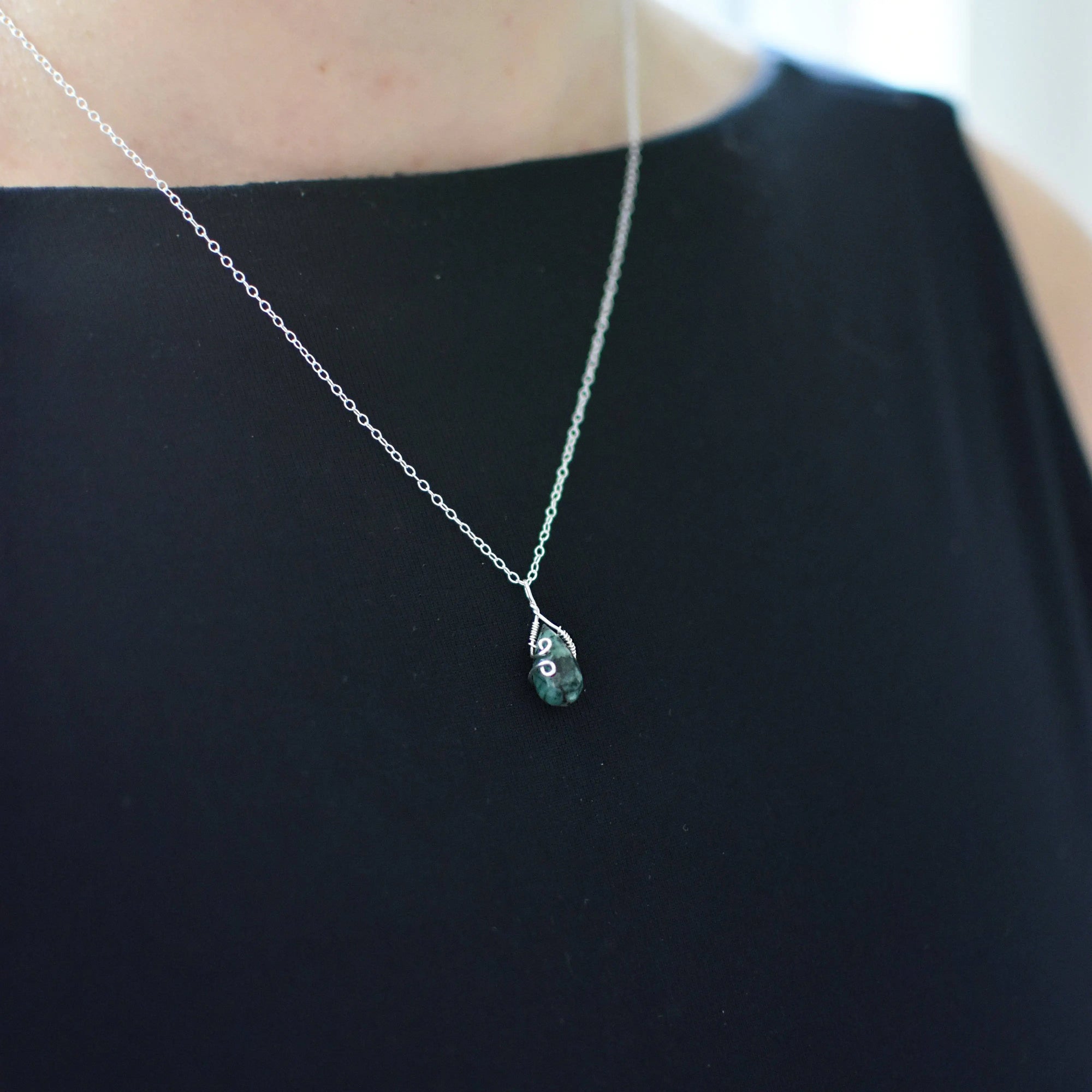 Minimalist emerald necklace for women worn on female model with natural faceted emerald in sterling silver