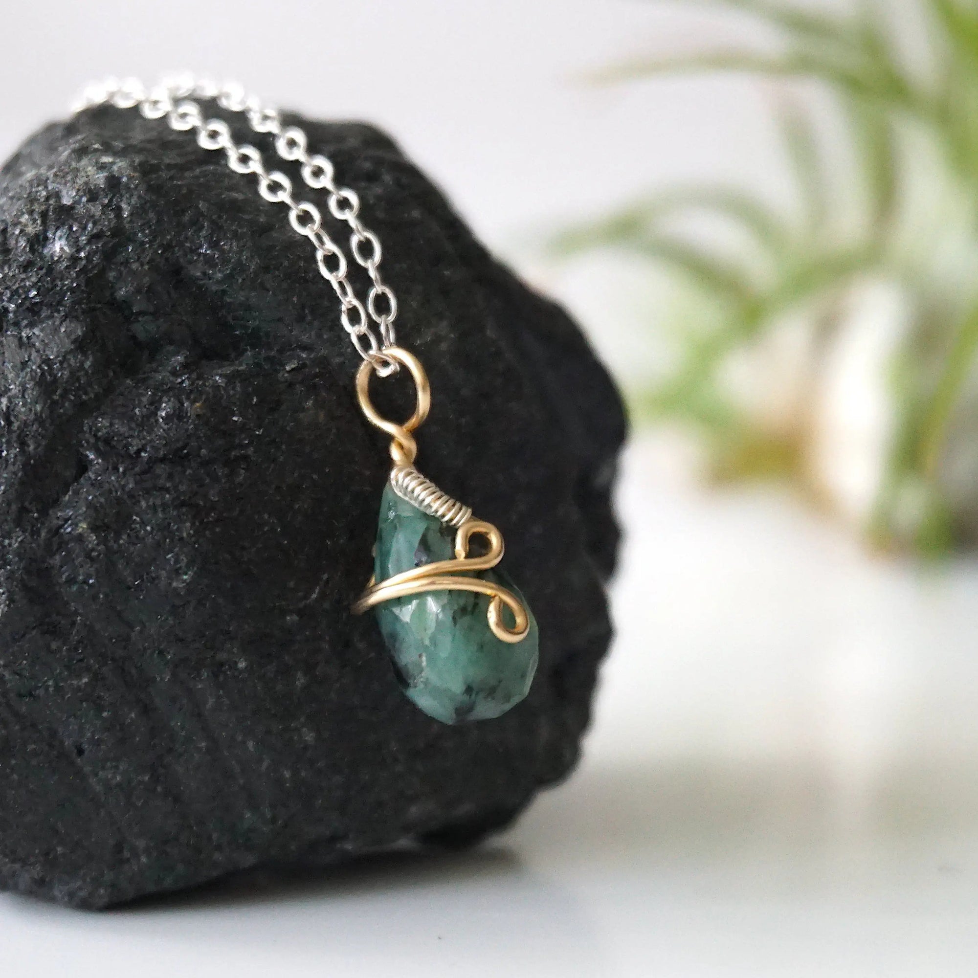 Right angle detail of minimalist emerald pendant for women with natural faceted emerald in 14k gold filled and sterling silver wrapping