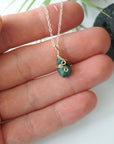 Minimalist emerald necklace for women shown in hand for size reference with natural faceted emerald and mixed metal wire wrapping