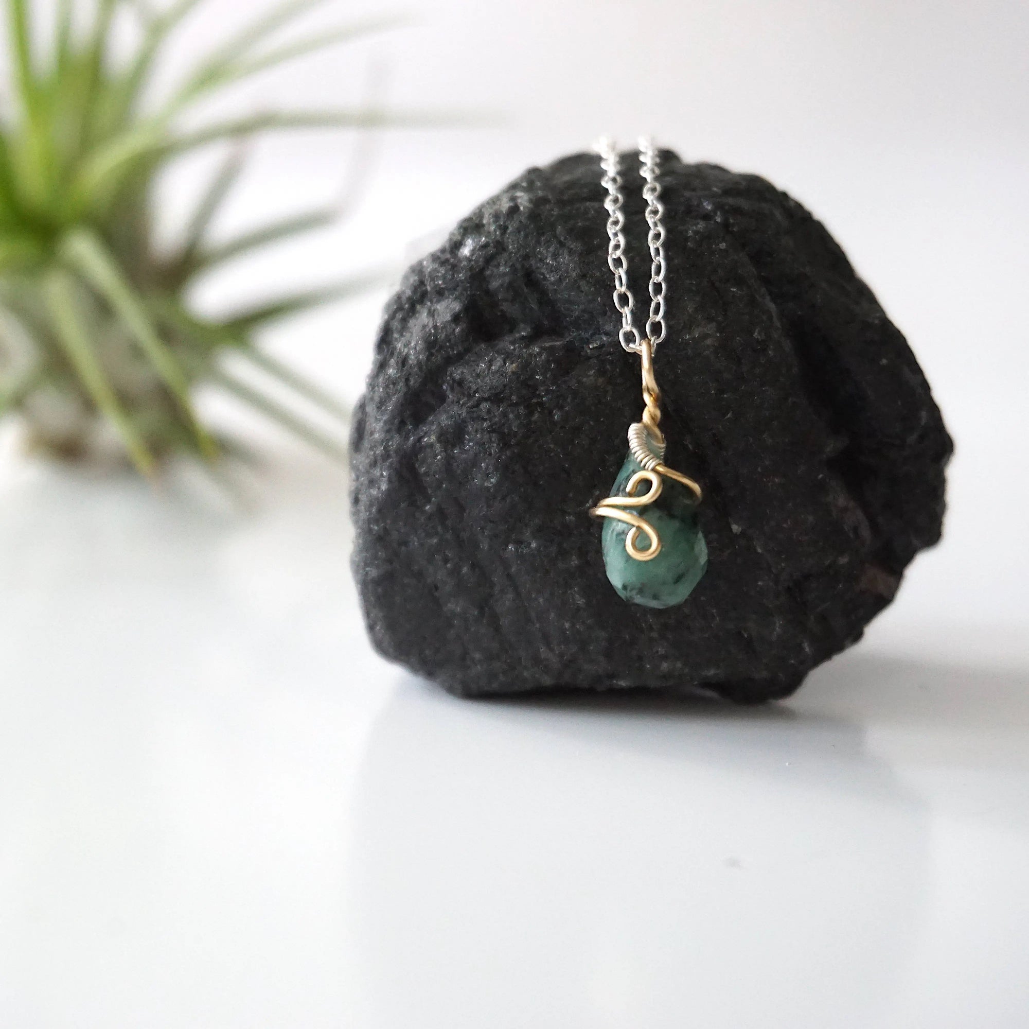Zoomed out view of minimalist emerald necklace for women with faceted teardrop emerald on sterling silver chain