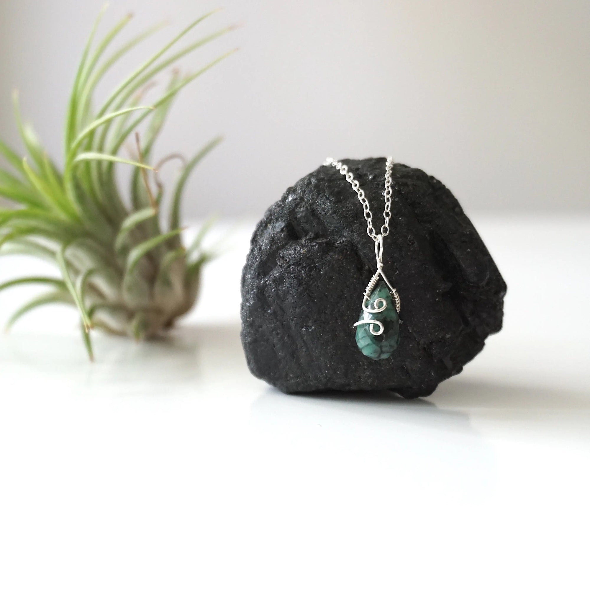 Zoomed out view of minimalist emerald necklace for women with faceted teardrop emerald on sterling silver chain