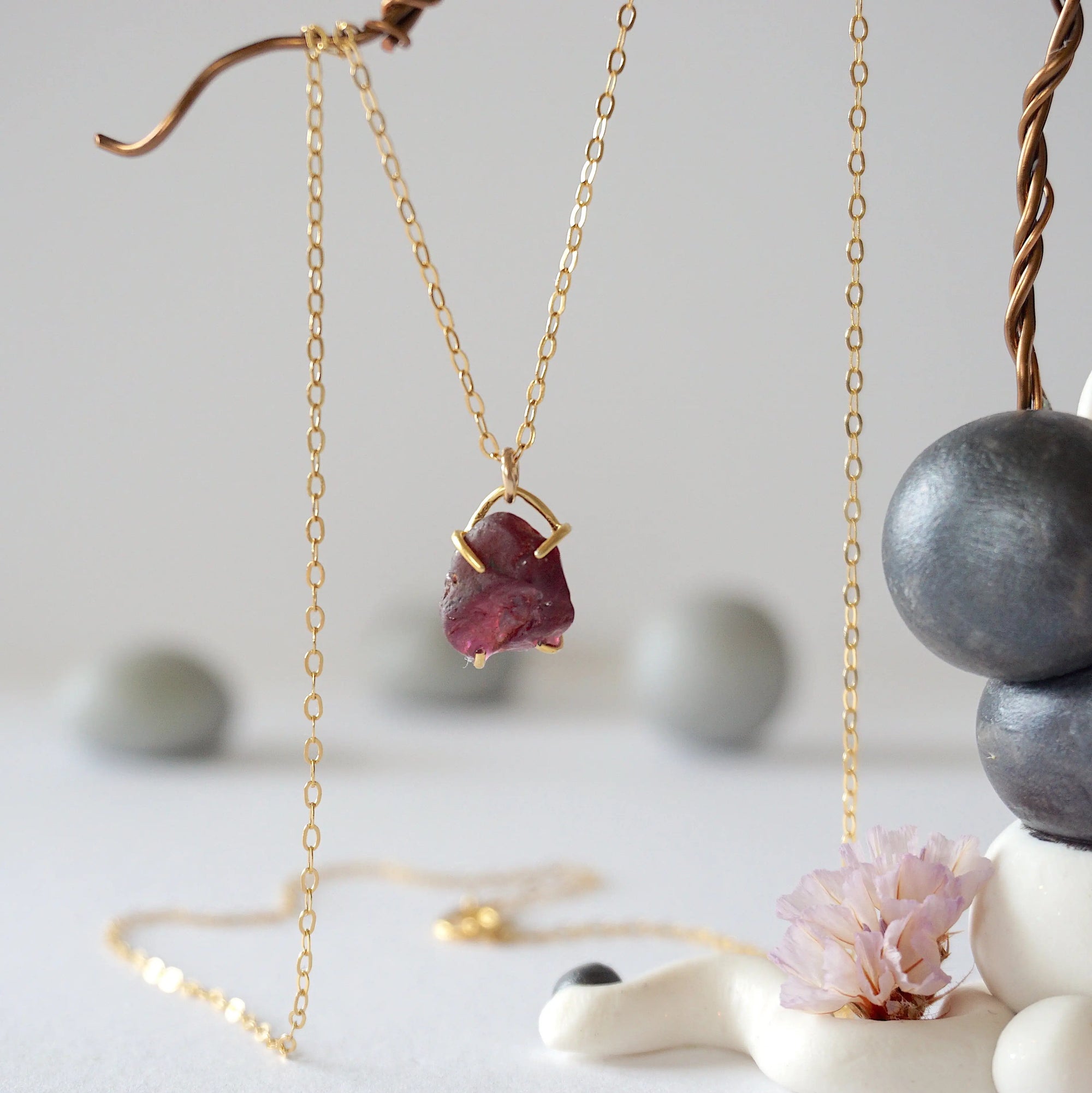 Close front view of minimalist raw garnet pendant in 14k gold vermeil claw setting on a 14k gold filled chain