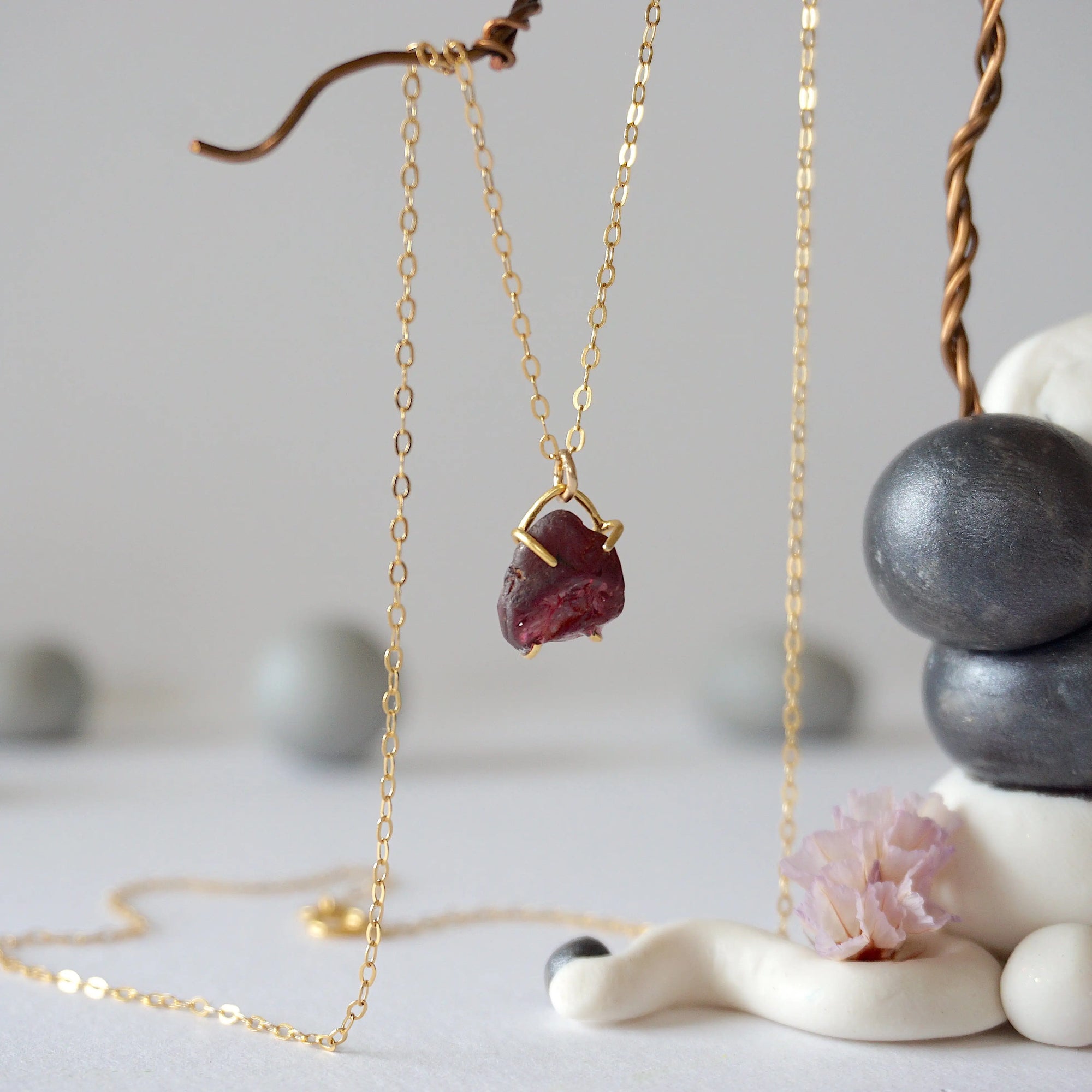 Side view of minimalist garnet pendant showing 14k gold vermeil claw setting and raw garnet texture on a 14k gold filled chain