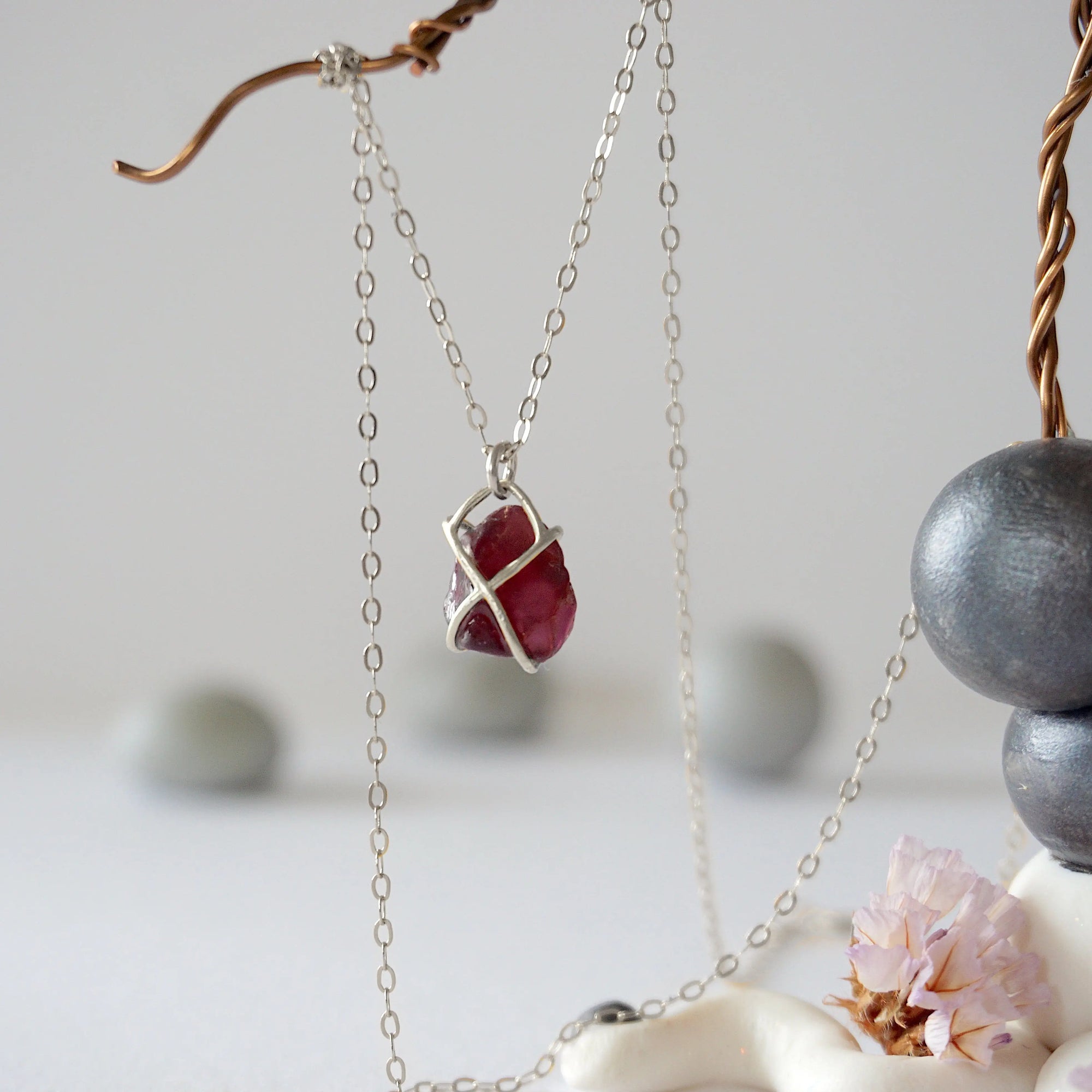 Back view of minimalist garnet pendant in sterling silver claw setting on a sterling silver chain