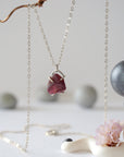 Close front view of minimalist raw garnet pendant in sterling silver claw setting on a sterling silver chain