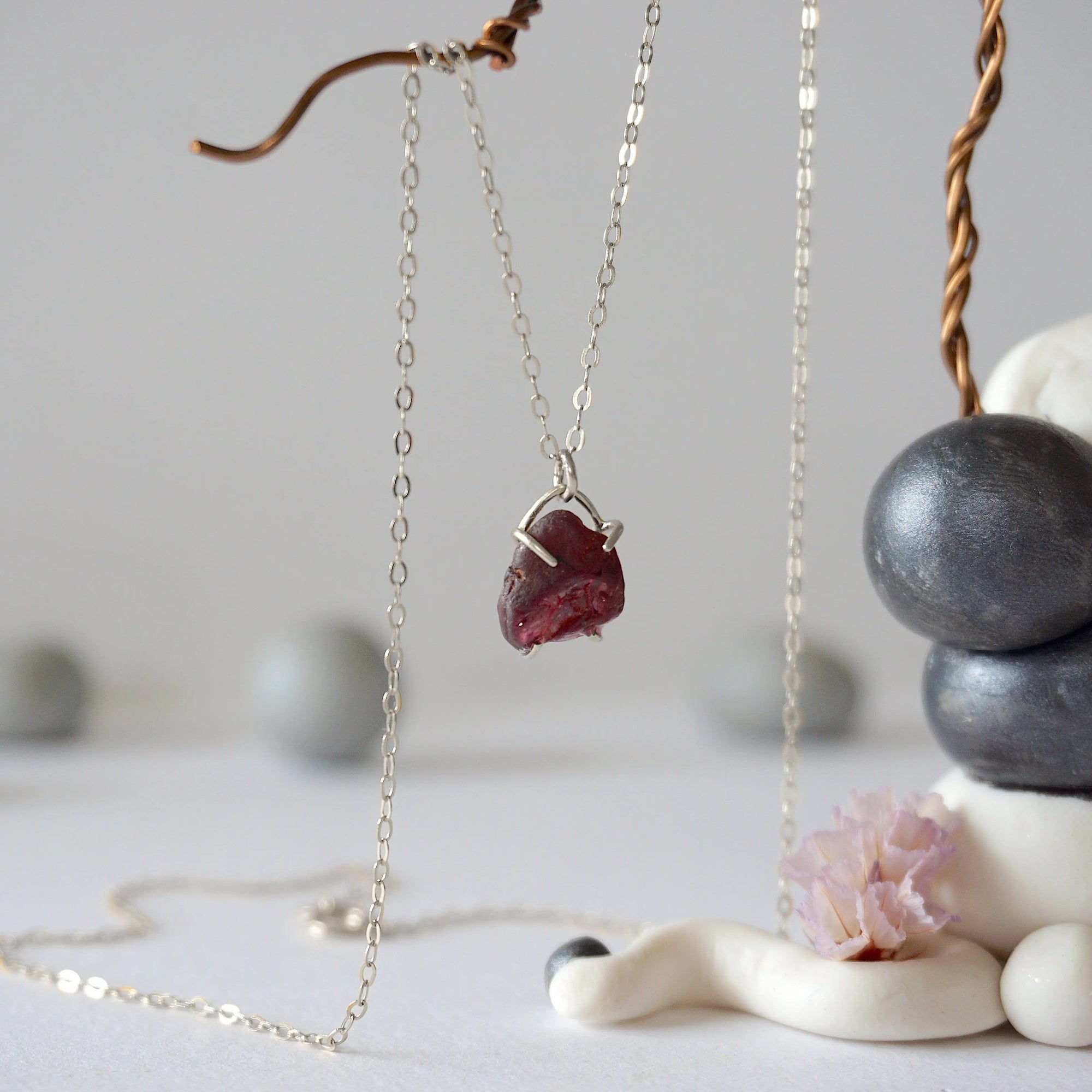 Side view of minimalist garnet pendant showing sterling silver claw setting and raw garnet texture on silver chain