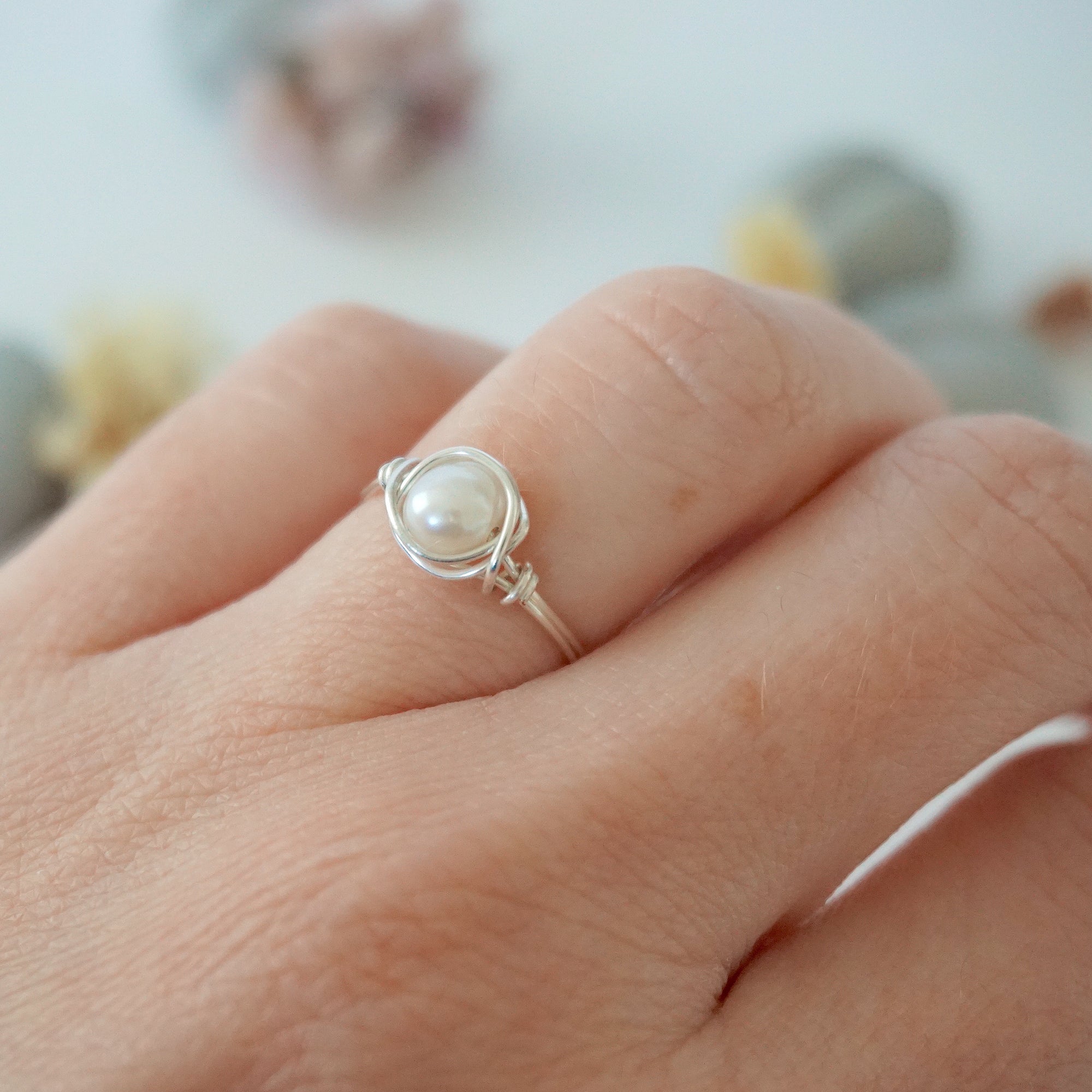 Minimalist pearl wire wrapped ring in sterling silver worn on a model’s hand