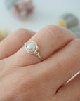 Minimalist pearl wire wrapped ring in sterling silver worn on a model’s hand