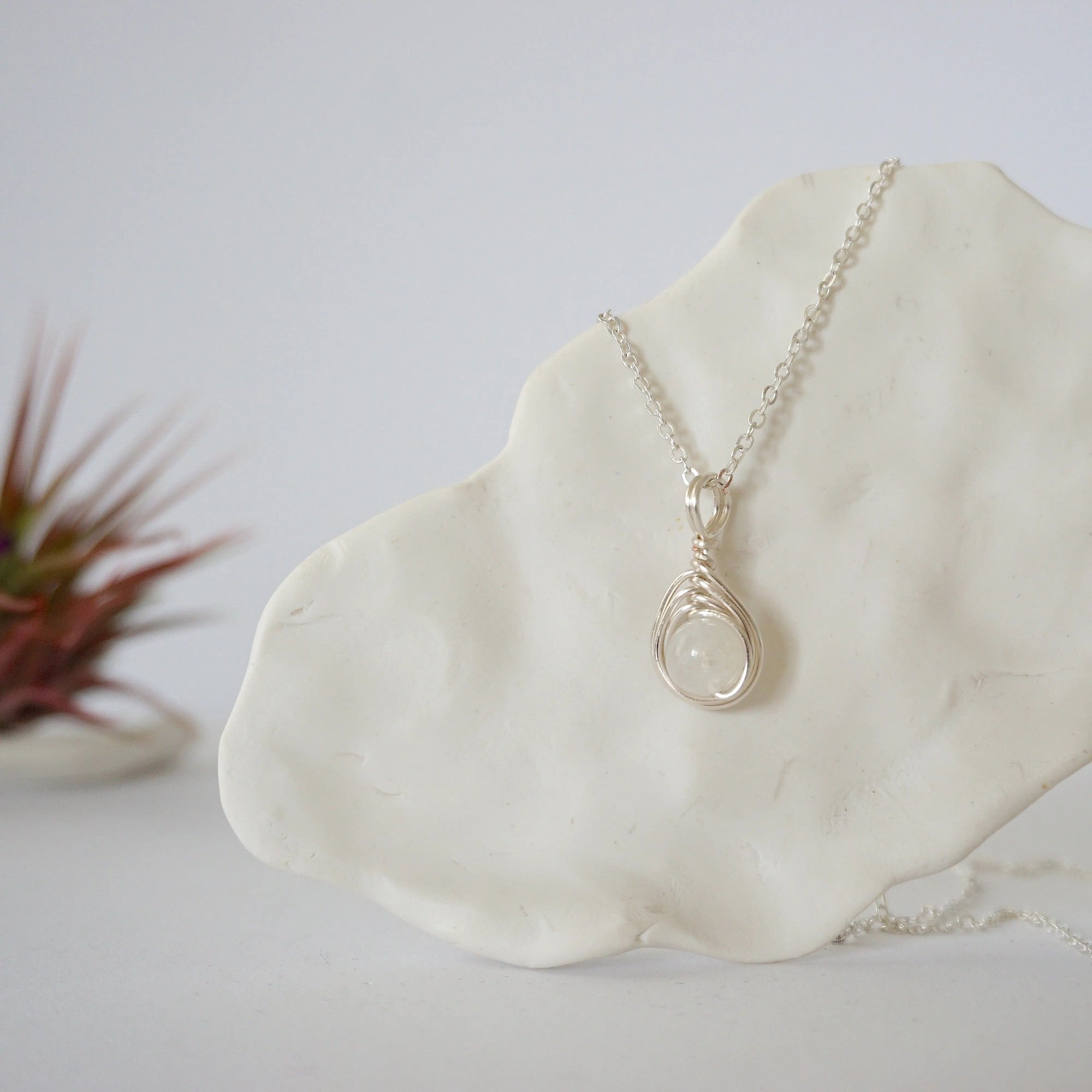 Close-up front view of minimalist rainbow moonstone necklace for women with natural 8mm moonstone bead in soft silver wire wrap (June birthstone).