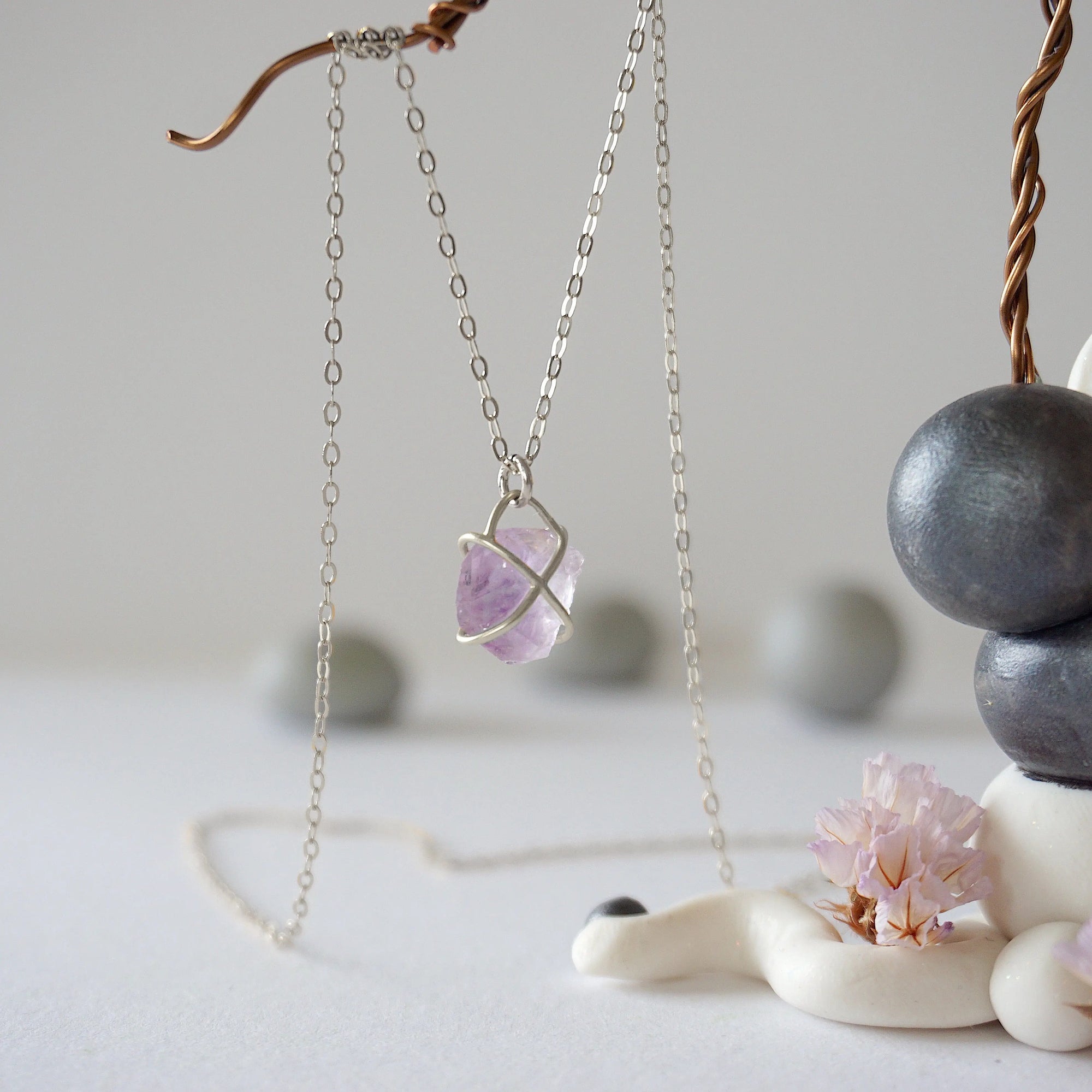 Back view of sterling silver claw setting holding natural raw amethyst stone on minimalist February birthstone necklace