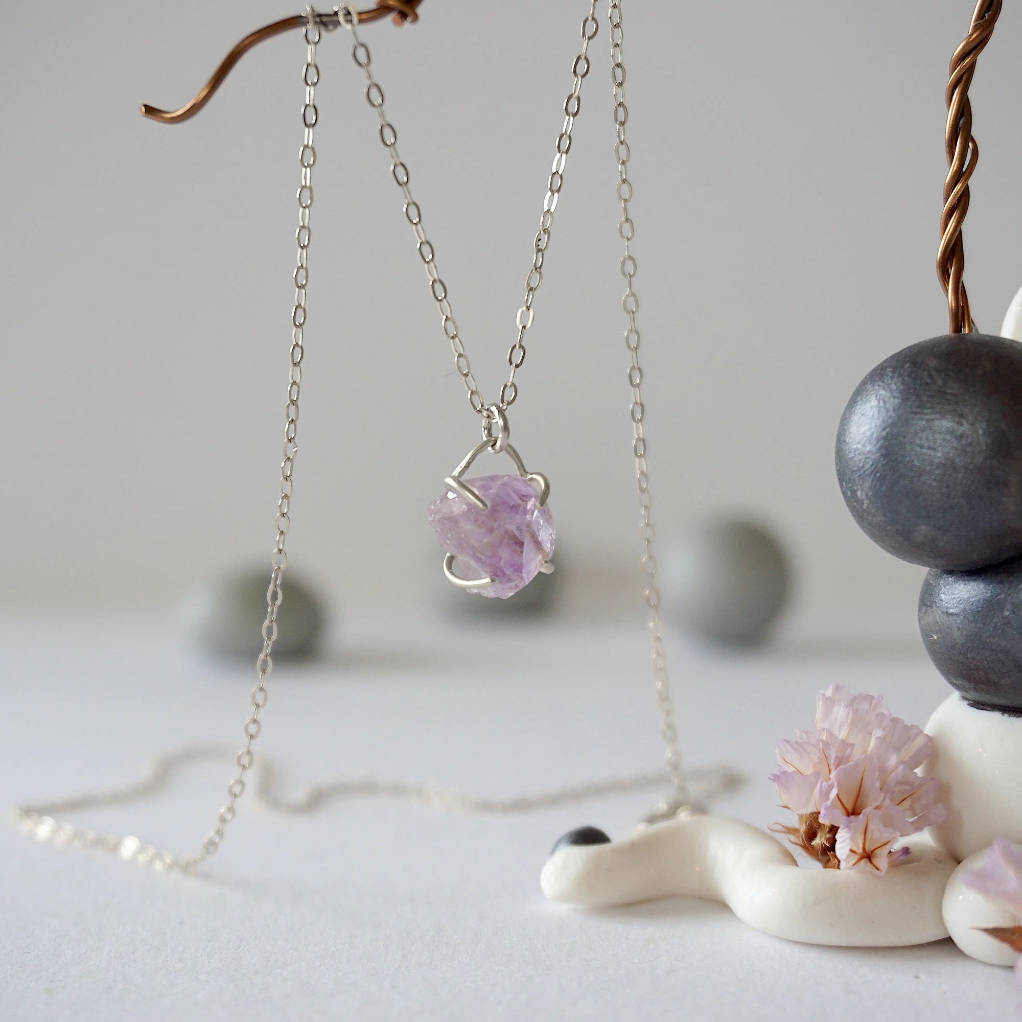 Side view of raw amethyst crystal pendant necklace in 925 sterling silver claw setting on sterling silver cable chain
