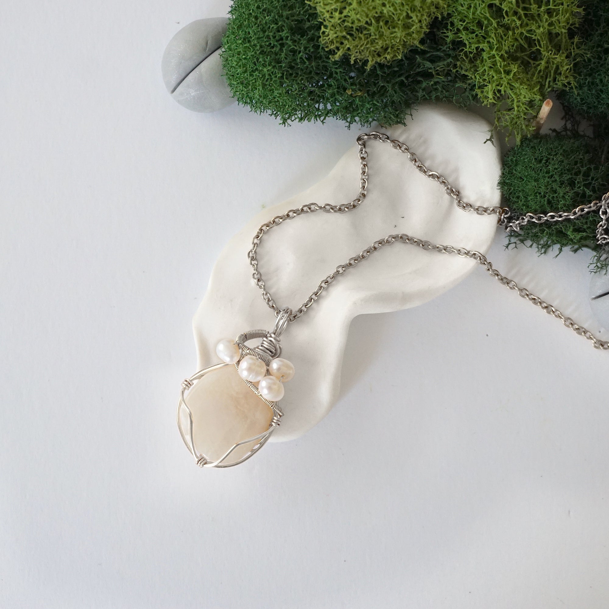 Handmade silver wire wrapped moonstone and freshwater pearl necklace laying flat on a silver plated chain, artisan jewelry for women