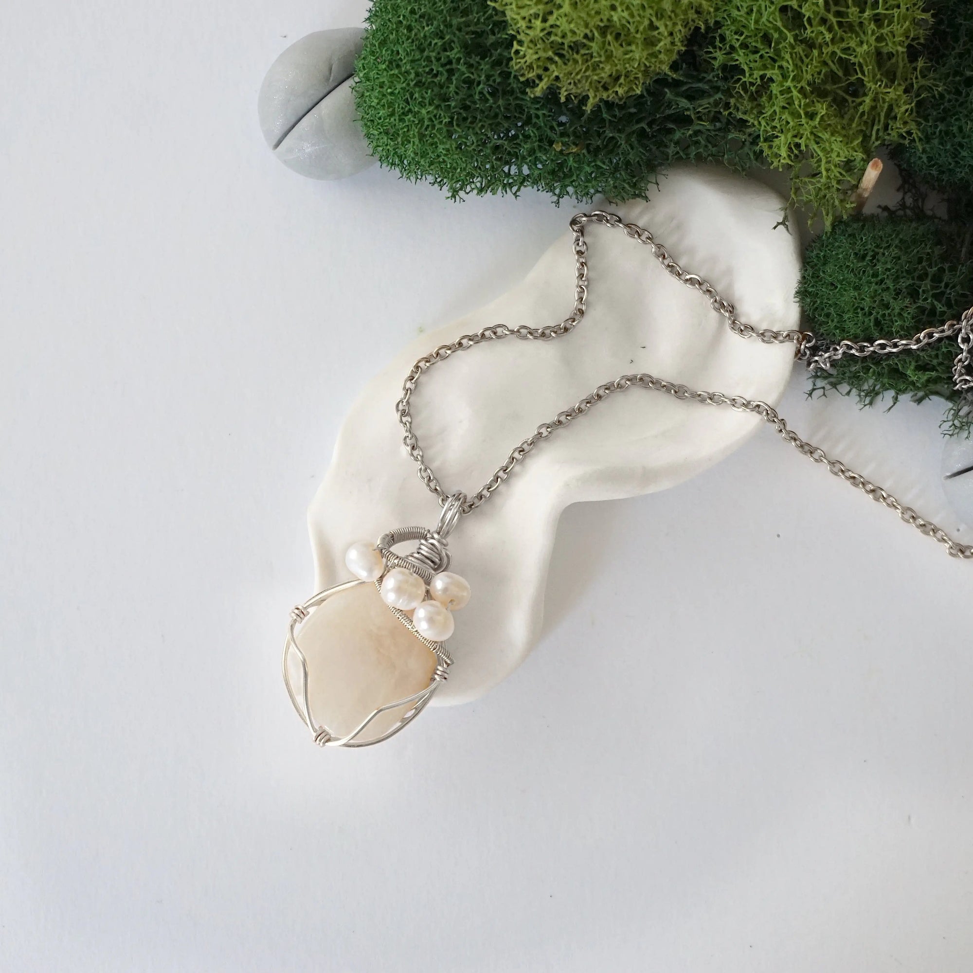 Handmade silver wire wrapped moonstone and freshwater pearl necklace laying flat on a silver plated chain, artisan jewelry for women