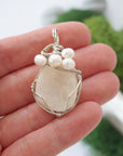 Moonstone and freshwater pearl pendant necklace in hand for size reference, silver wire wrapped, handcrafted gemstone jewelry
