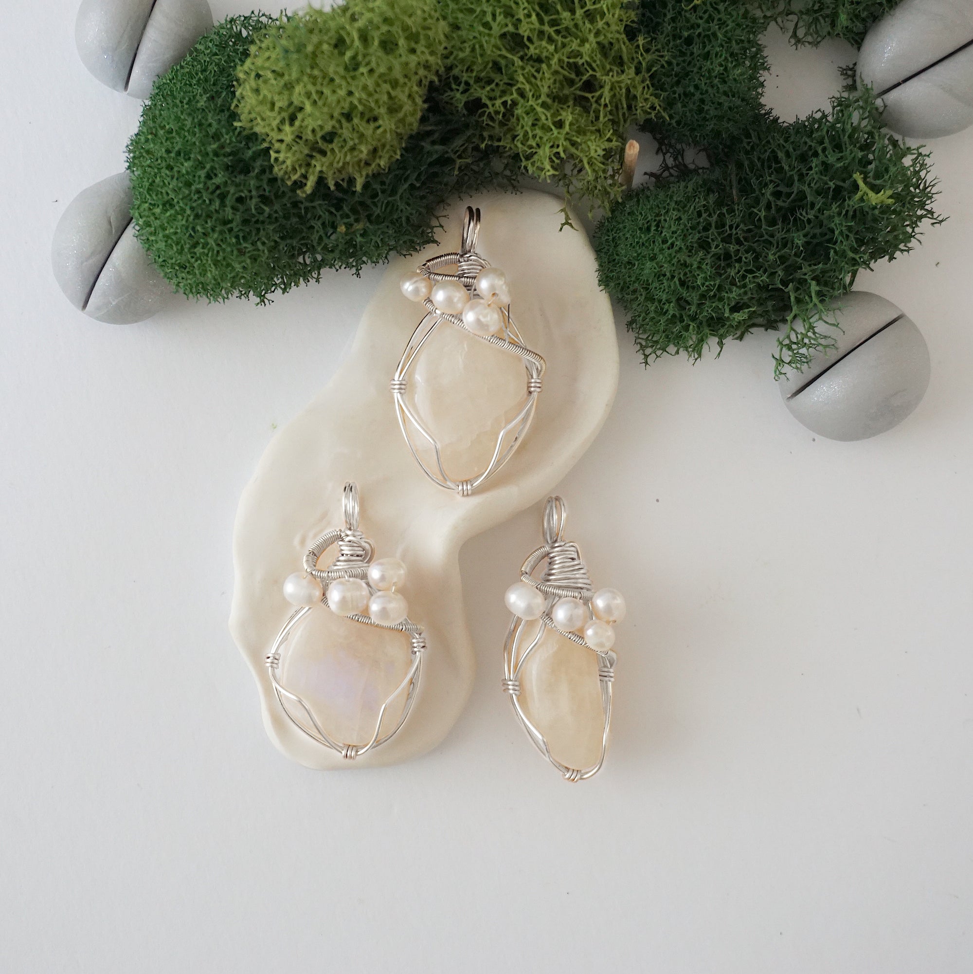 Three silver wire wrapped moonstone and freshwater pearl pendants showing natural stone variation, artisan jewelry for women