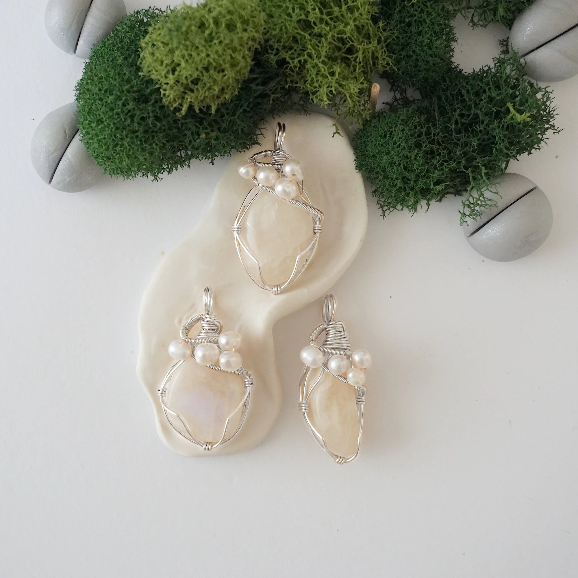 Three silver wire wrapped moonstone and freshwater pearl pendants showing natural stone variation, artisan jewelry for women
