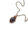 Natural garnet necklace with raw crystal pendant on antique bronze copper chain laying flat