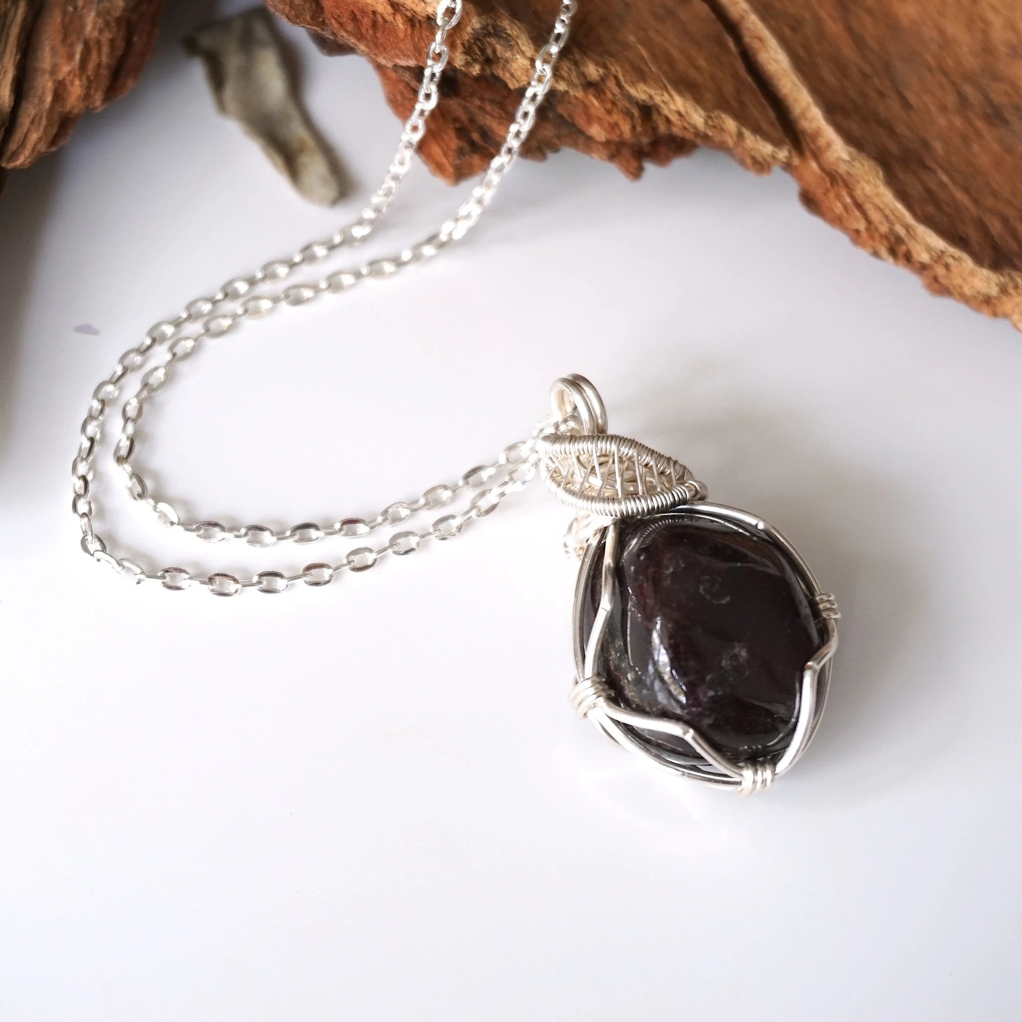 Natural garnet necklace with raw crystal pendant on silver plated brass cable chain laying flat
