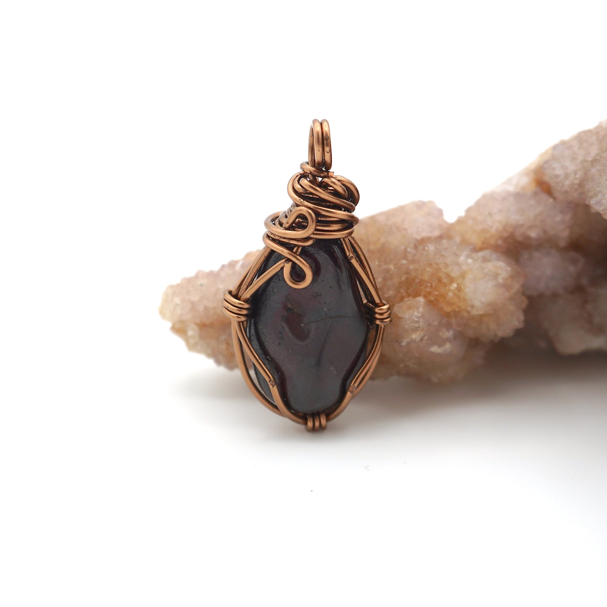 Back angle of raw garnet pendant showing wire wrapping and natural crystal texture