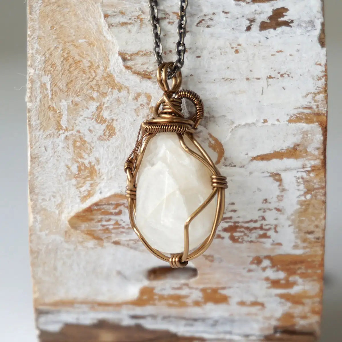Back view of antique bronze wire wrapped moonstone pendant, showing handcrafted wrapping details and secure setting.