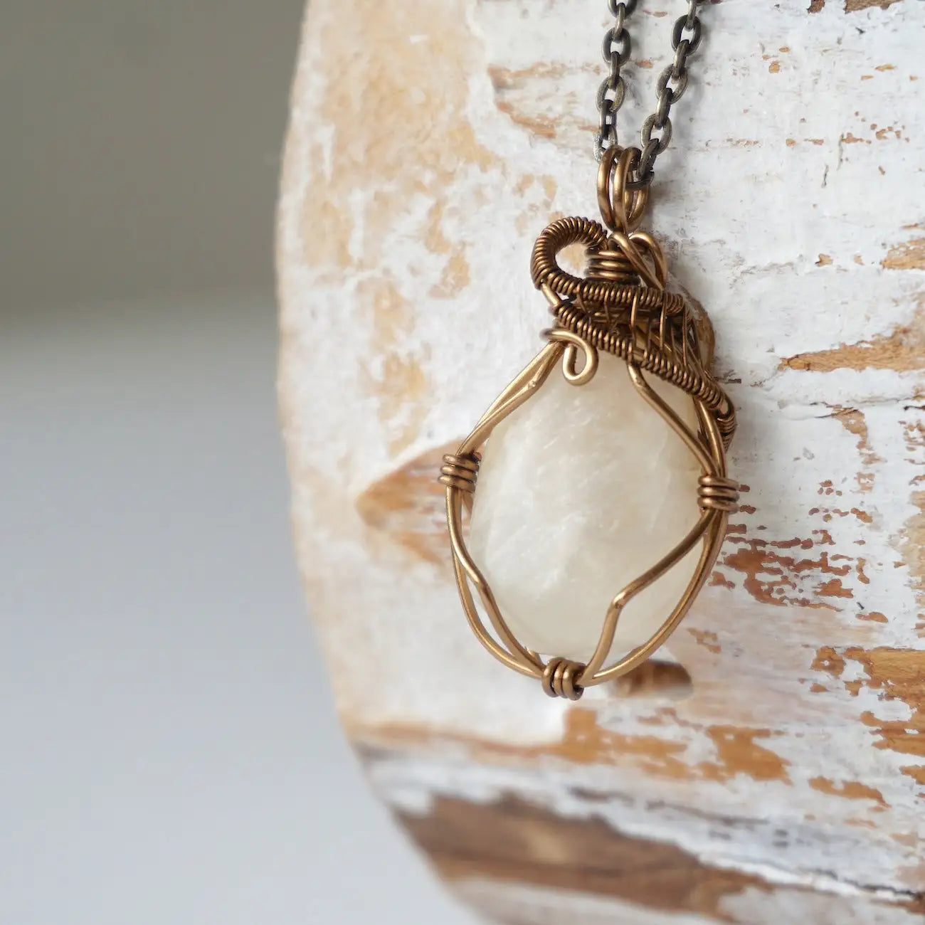 Left angle close-up of natural moonstone pendant necklace, antique bronze wire wrapped setting showing handcrafted detail.