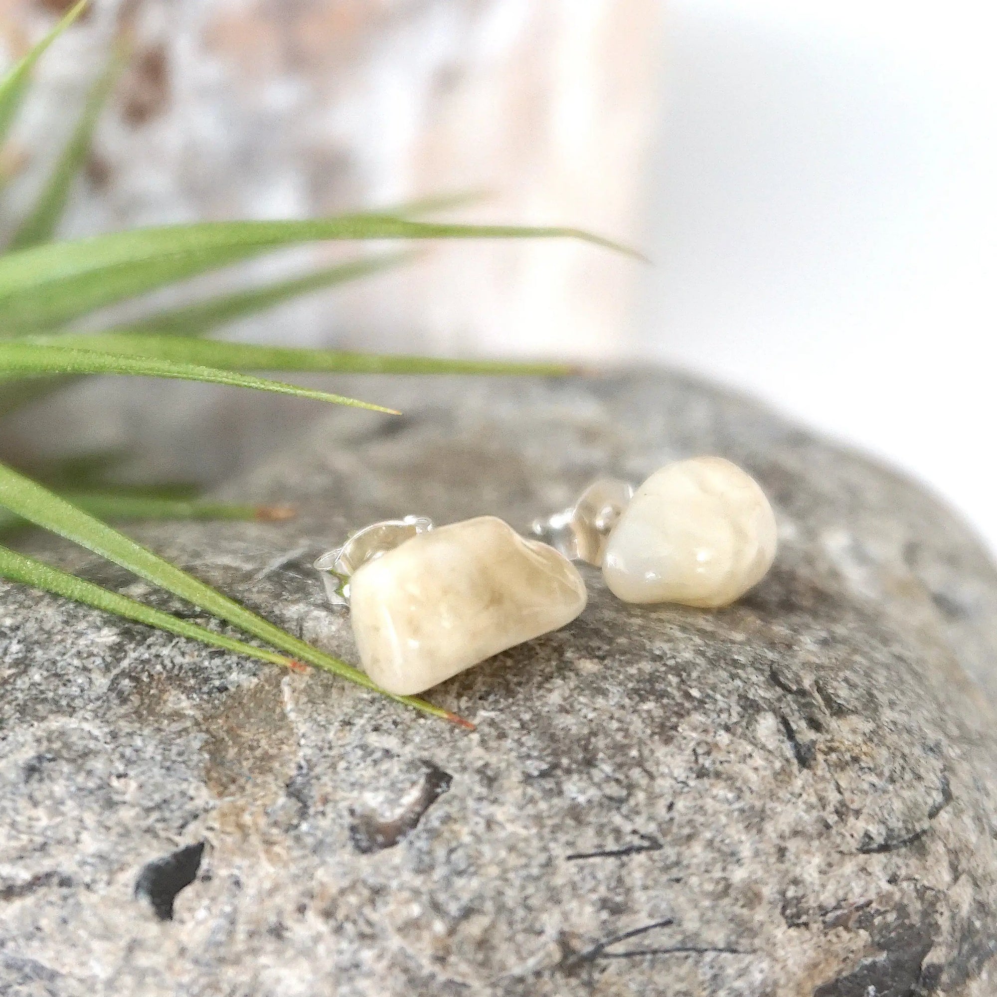 Right angle close-up of natural moonstone stud earrings showing polished stone surface and minimalist sterling silver post setting.