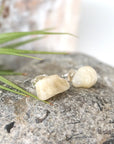 Right angle close-up of natural moonstone stud earrings showing polished stone surface and minimalist sterling silver post setting.