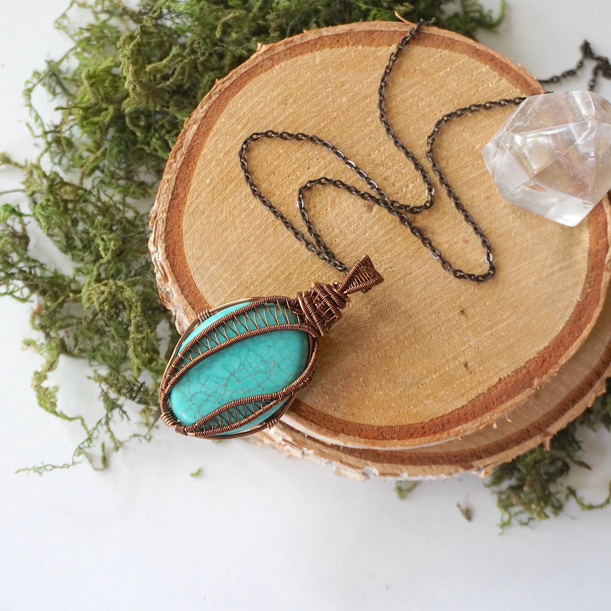 Natural turquoise necklace for women with intricate antique bronze wire wrapped pendant on 24 inch chain laying flat
