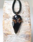 Detailed front view of men’s black obsidian arrowhead necklace on black leather cord, antique bronze copper wire wrap, by Designs by Nature Gems.