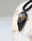 Side angle detail of men’s black obsidian arrowhead necklace, antique bronze copper wire wrap, on black leather cord by Designs by Nature Gems.