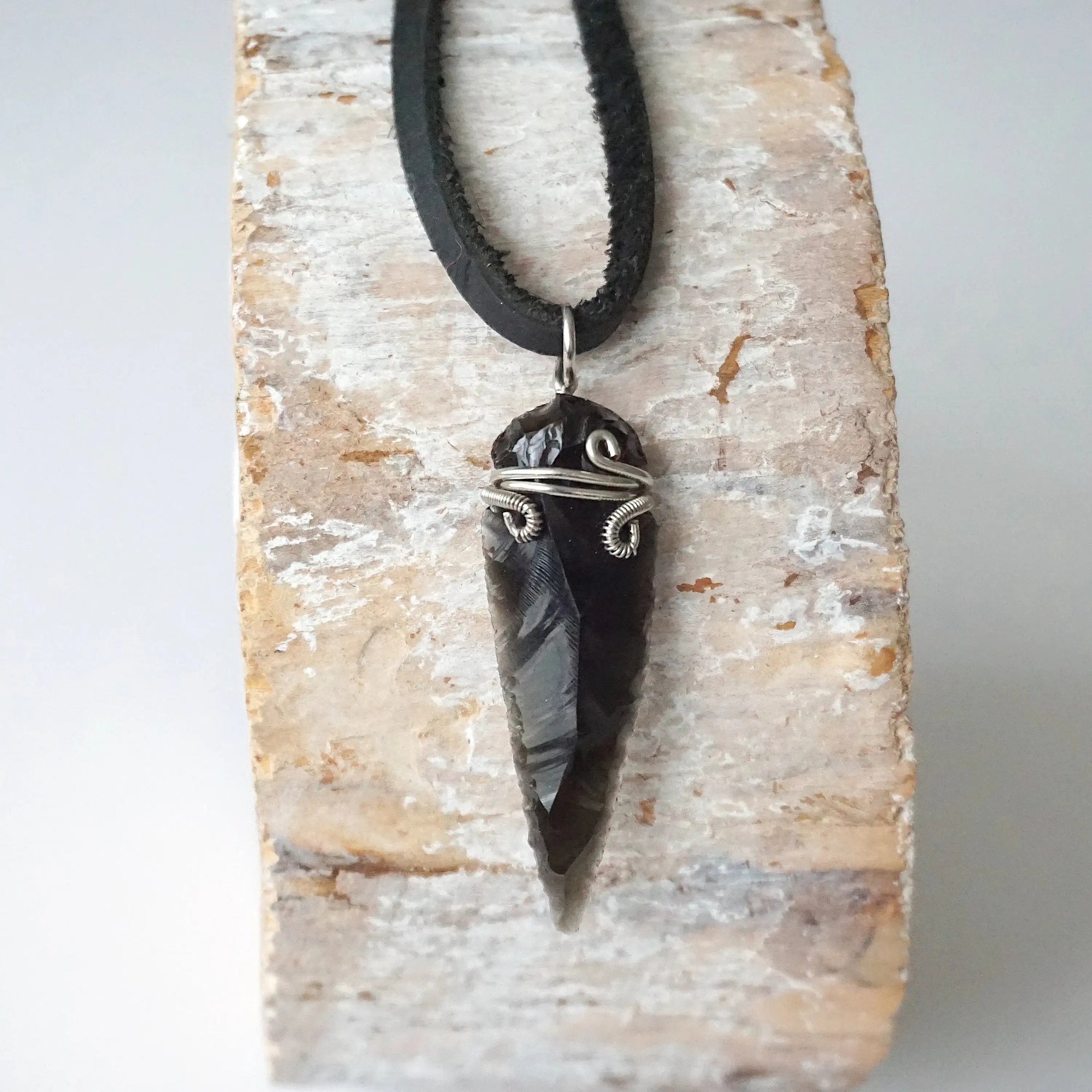 Detailed front view of men’s black obsidian arrowhead necklace on black leather cord, handcrafted crystal pendant by Designs by Nature Gems.