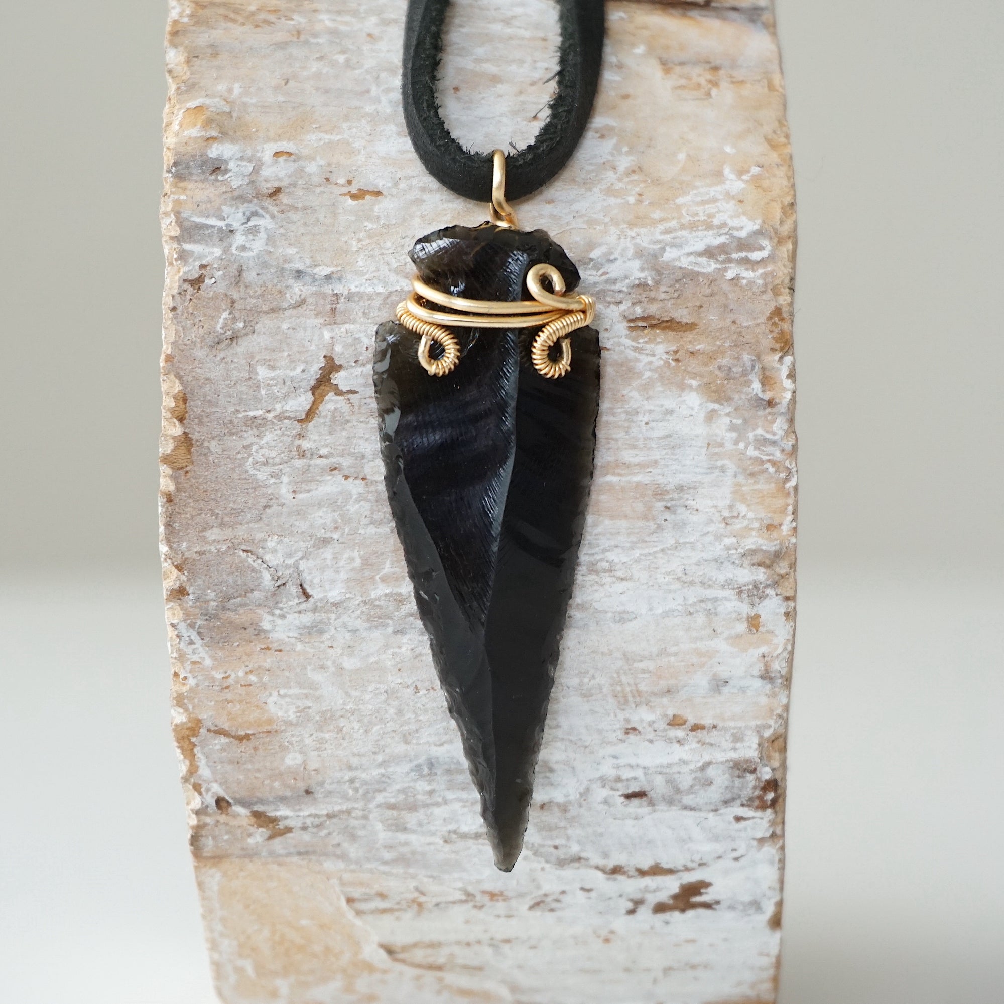 Detailed front view of men’s black obsidian arrowhead necklace on black leather cord, gold plated copper wire wrap, by Designs by Nature Gems.