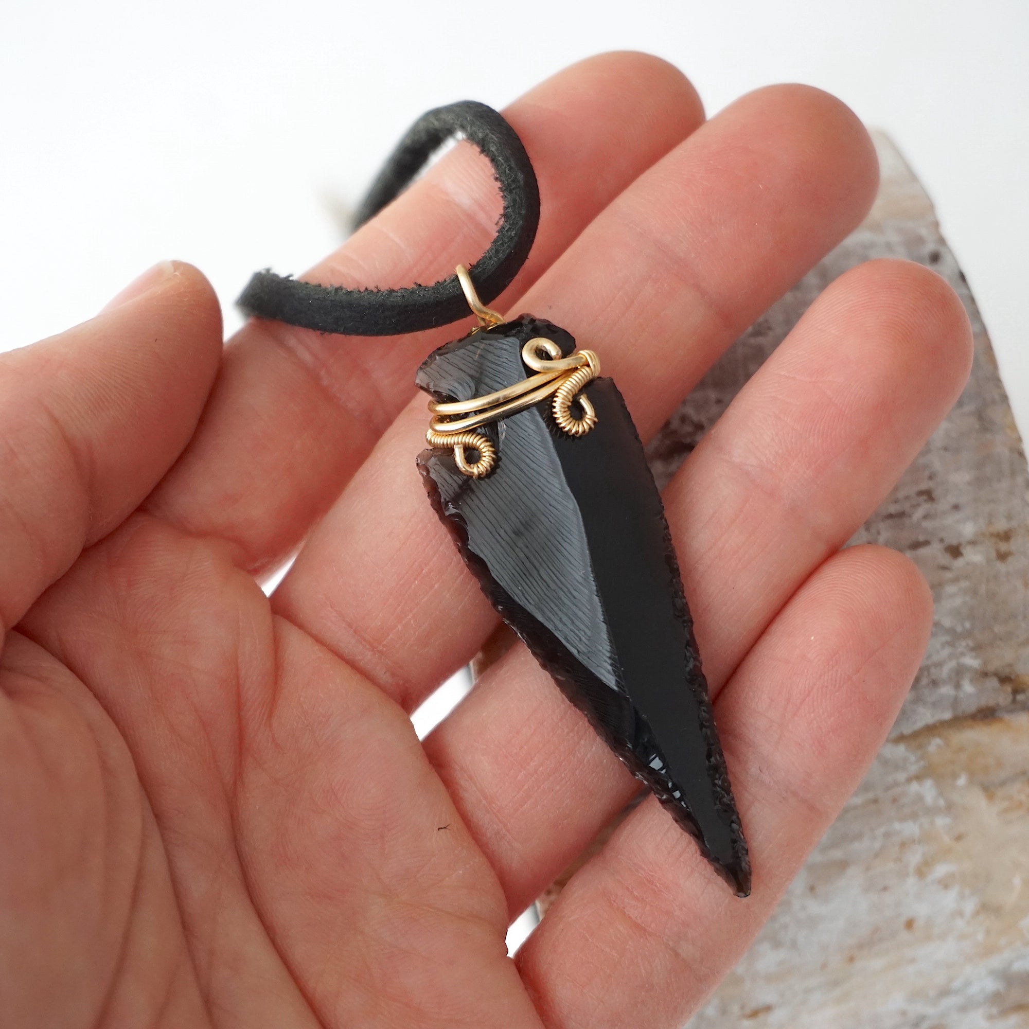 Black obsidian arrowhead necklace for men with gold plated copper wire wrap, shown in hand for size reference, by Designs by Nature Gems.