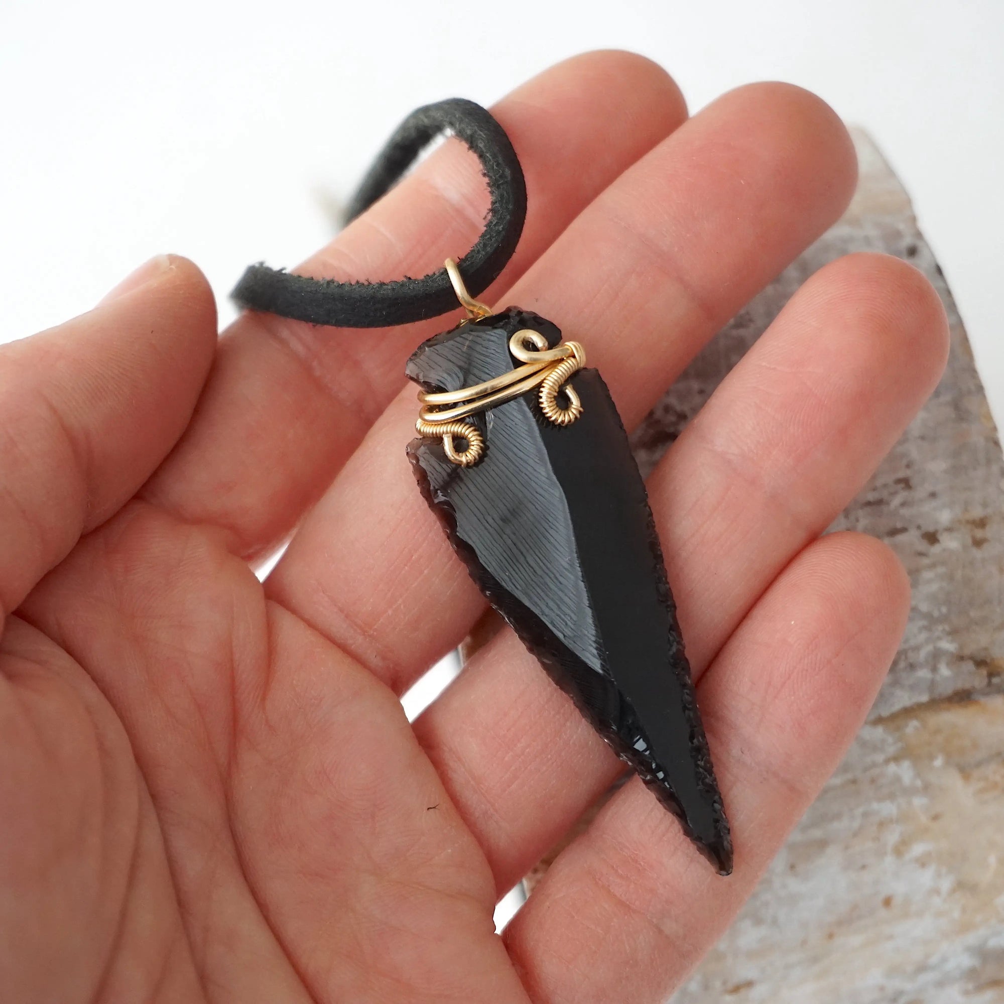 Black obsidian arrowhead necklace for men with gold plated copper wire wrap, shown in hand for size reference, by Designs by Nature Gems.
