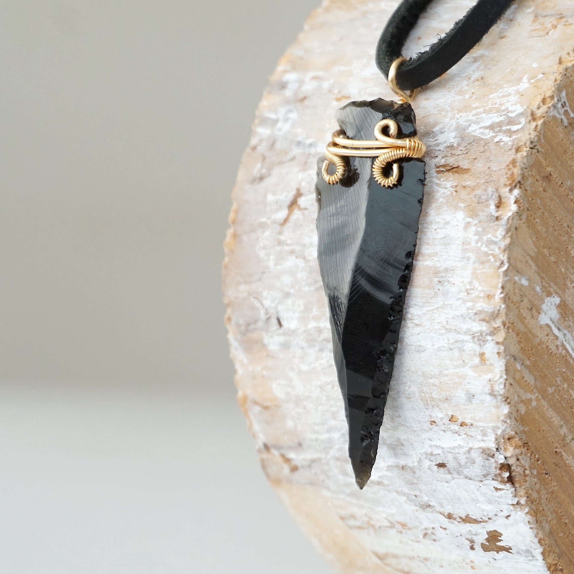Side angle detail of men’s black obsidian arrowhead necklace, gold plated copper wire wrap, on black leather cord by Designs by Nature Gems.