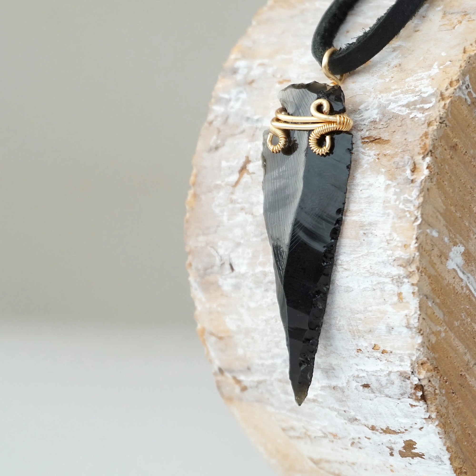Side angle detail of men’s black obsidian arrowhead necklace, gold plated copper wire wrap, on black leather cord by Designs by Nature Gems.