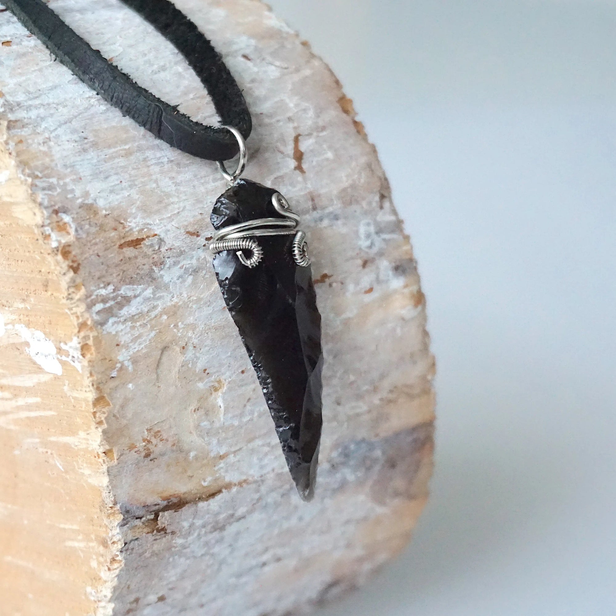 Side angle detail of men’s black obsidian arrowhead necklace, wire wrapped crystal pendant on black leather cord by Designs by Nature Gems.