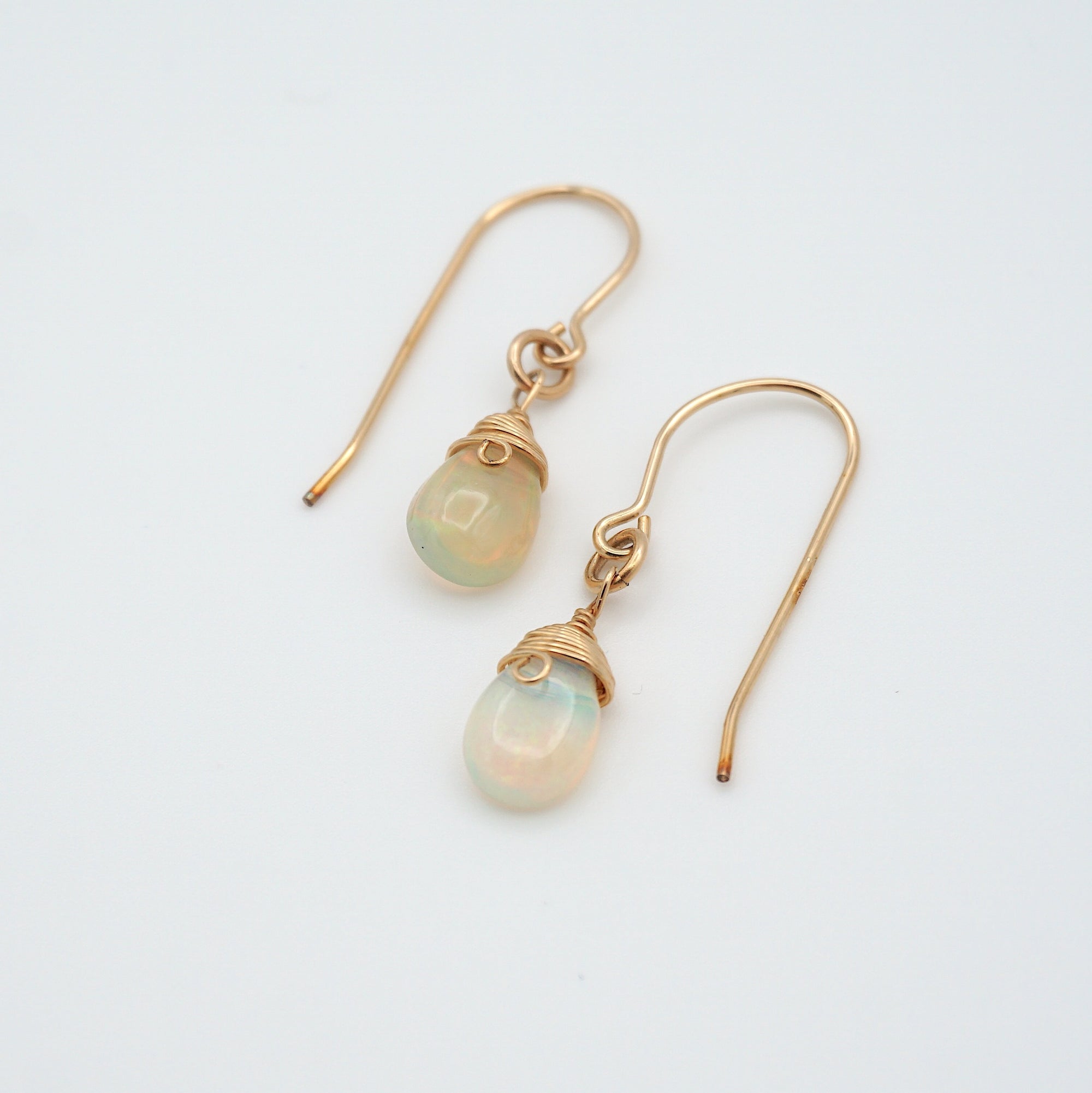 Angled look at opal drop earrings, artisan wire wrapping in 14k gold filled, October birthstone
