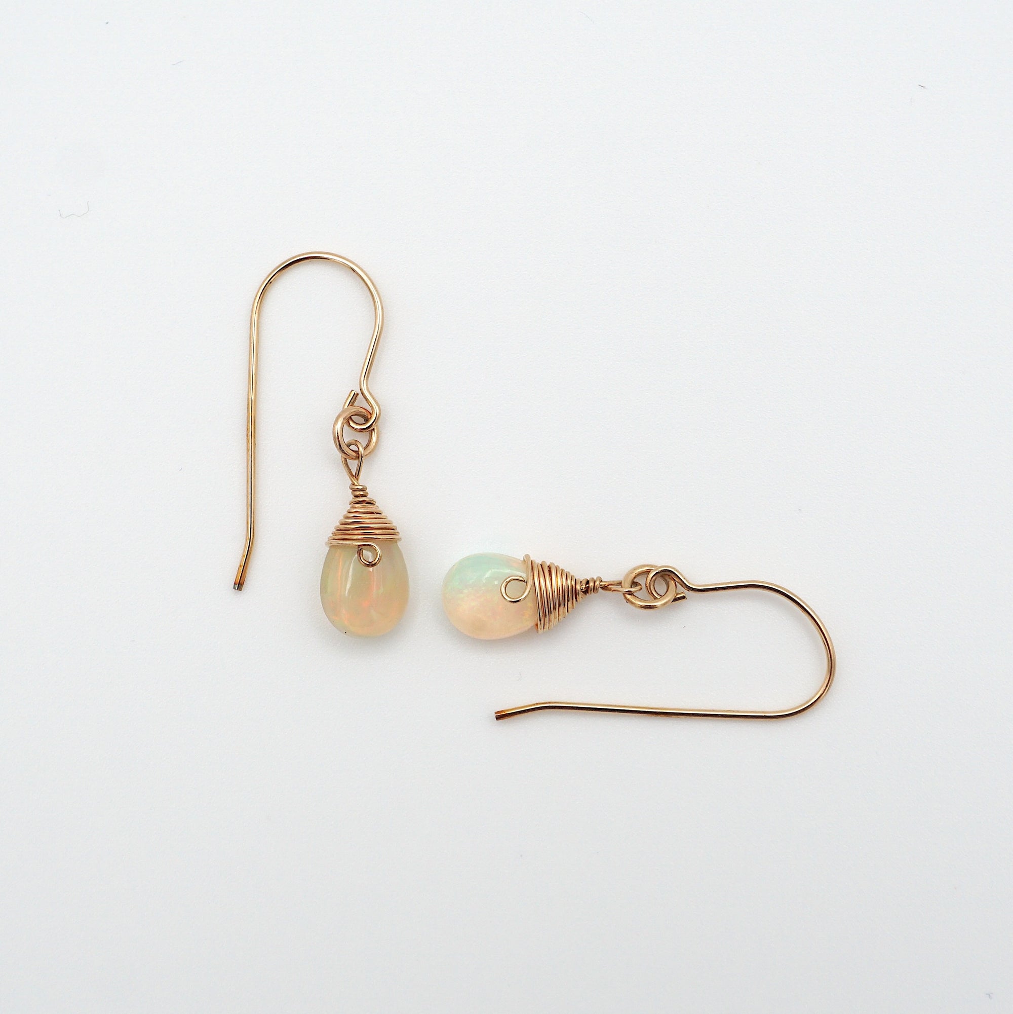 Closeup showing details of opal drop earrings, faceted opal stone, 14k gold filled setting