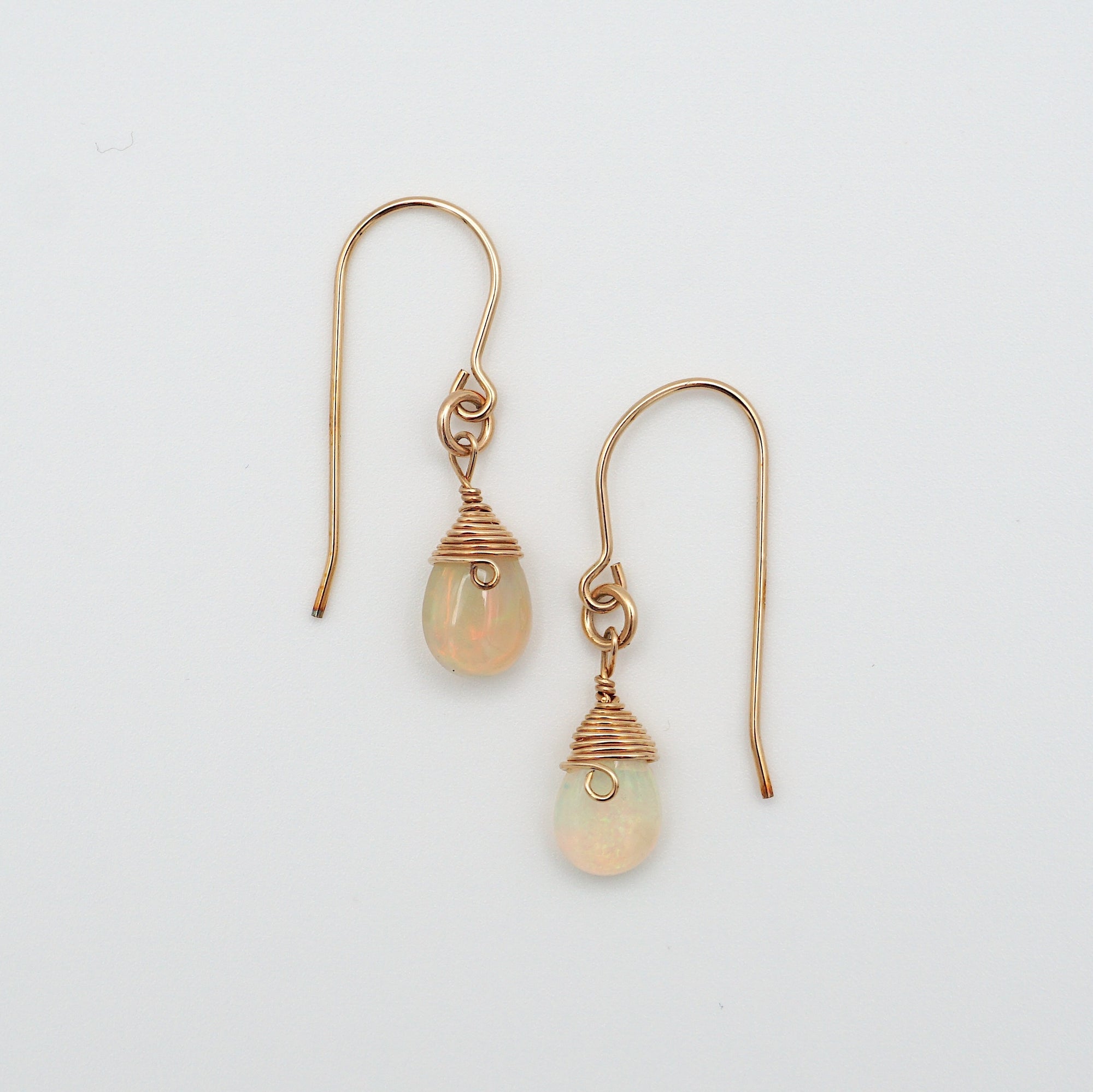 Detailed front view of opal drop earrings, natural faceted opal with minimalist 14k gold filled wire wrapping, Designs by Nature Gems